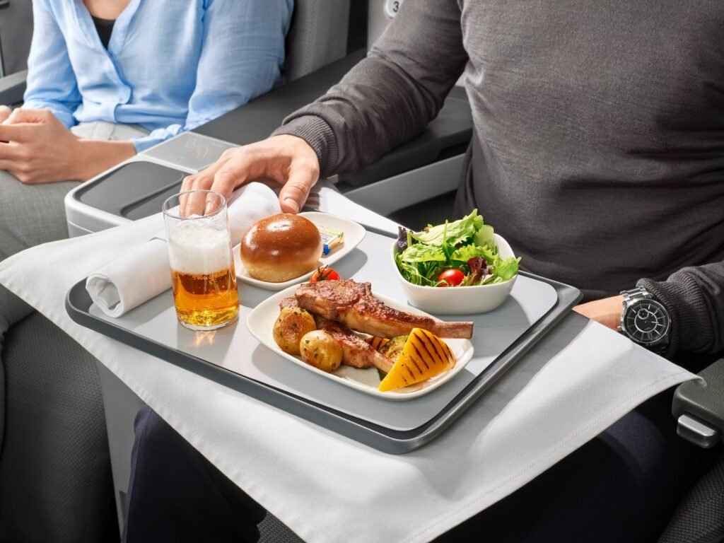 Bier, Salat, Brot und Hähnchenschenkel werden serviert in der Business Class von Eurowings Discover